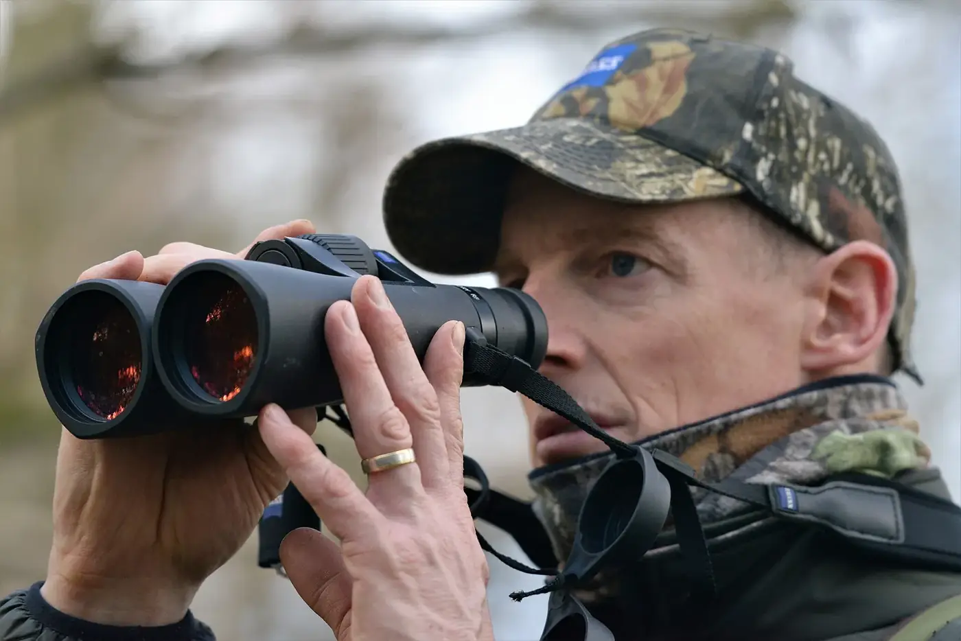 Hunter in camouflage glassing with binoculars