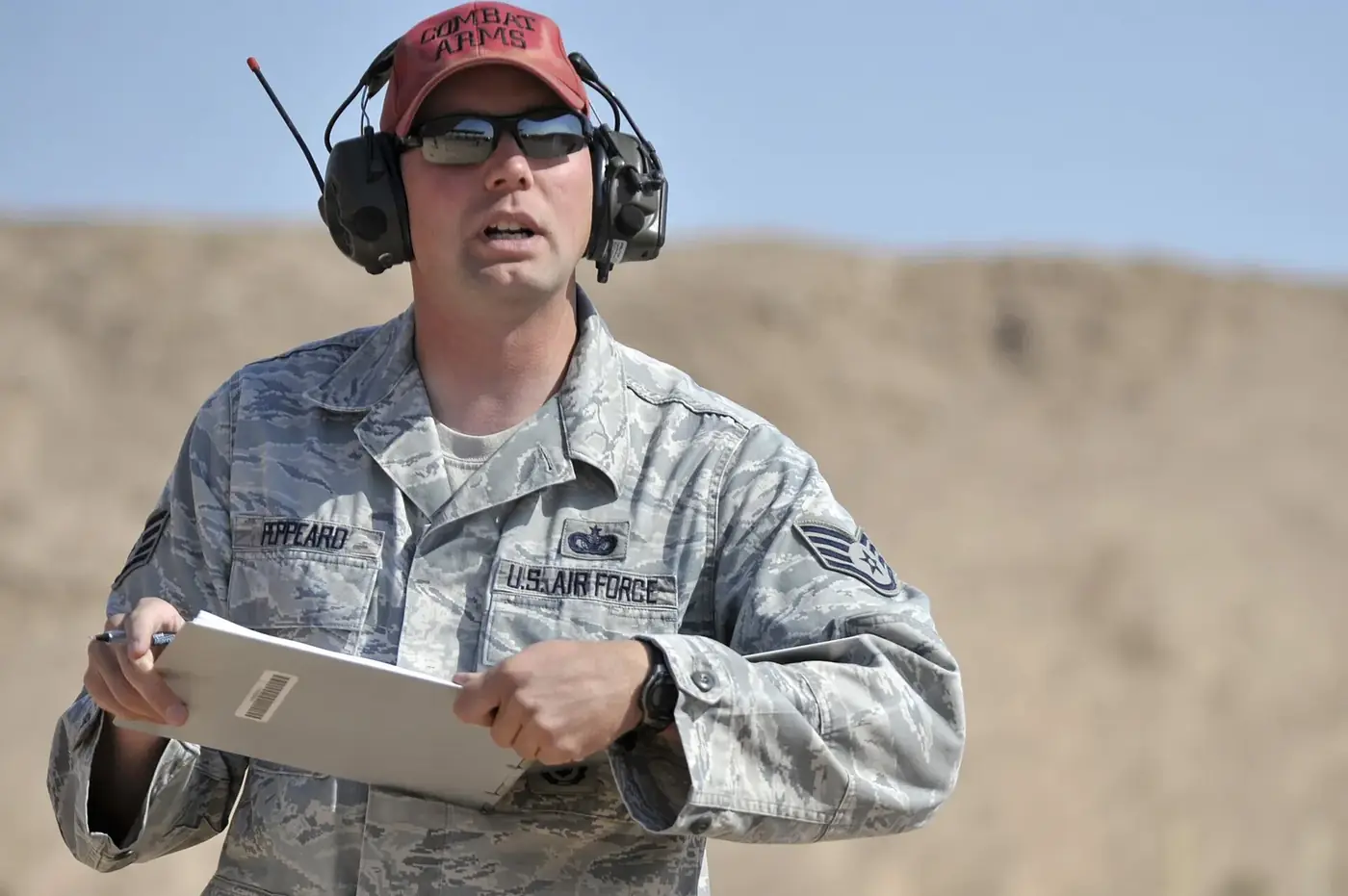 Range officer wearing tinted shooting glasses and electronic earmuffs at an outdoor range