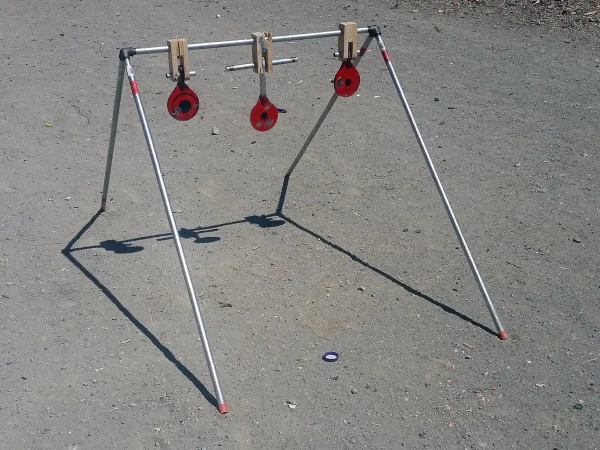Three red steel plate targets hanging from a portable target stand
